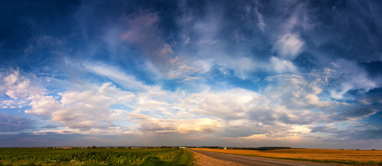 Summer road under awesome clouds on the sky panorama