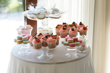 Round table with luxurious cupcakes and macaroons