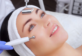 The cosmetologist makes the apparatus a procedure of Microcurrent therapy of a beautiful, young woman in a beauty salon. Cosmetology and professional skin care.