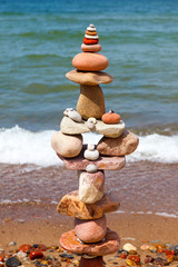 Fototapeta na wymiar High pyramid of multicolored pebbles on a background of the summer sea.