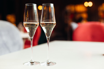 Close-up of two glasses with champagne on a table with a white c