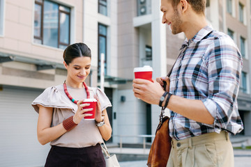Favourite drink. Pleasant good looking woman holding a cup of coffee while standing together with her friend