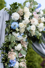 The range of flowers of gentle hues on a wedding arch.