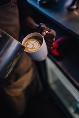 Pouring Latte Art into a cup of coffee by barista at a coffee shop cafe