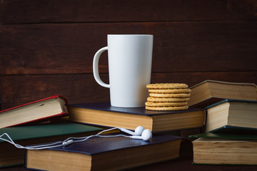 White Cup With Hot Coffee and Headphones on Deployed Books on a