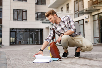 Being awkward. Nice handsome man taking a book from the ground after dropping it