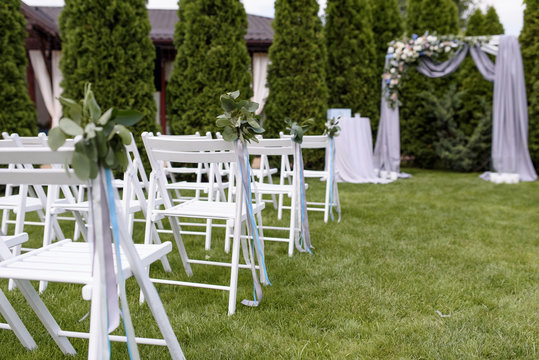 Green buttonholes on white chairs.