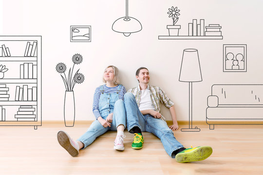 Photo of man and woman sitting on floor with painted on wall house flowers , paintings, sofa, shelving
