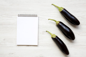 Fresh raw eggplant with notebook, top view. Blank space.