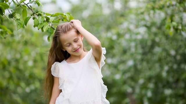 Adorable little girl in blooming apple garden on beautiful spring day