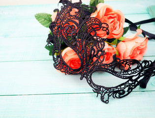 Masks with rose.black mask next to the roses on wooden background