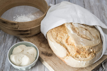 pane di semola con lievito madre fatto in casa con setaccio e farina e ciotola con lievito madre e tagliere di legno