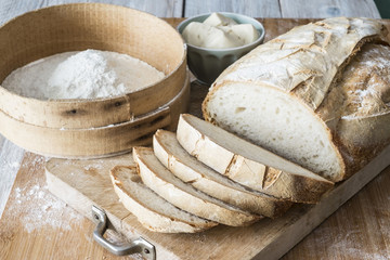 pane di semola con lievito madre fatto in casa con setaccio e farina e ciotola con lievito madre e...