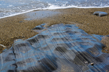 pebble stones on the sea beach, the rolling waves of the sea with foam