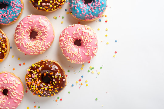 Variety of colorful tasty glazed donuts on a white background