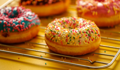 Variety of colorful tasty glazed donuts on a colored background