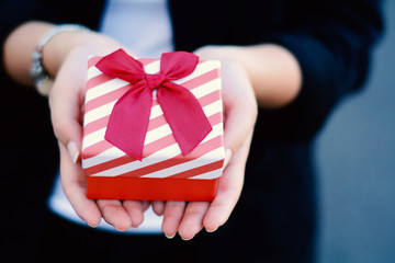 Female hands holding a gift box, present.