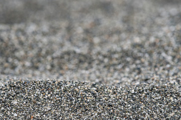 Close up of black, white, gray and brown stone pacific beach sand with a shallow depth of field and copy space