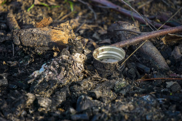 The lid of vodka lies on the ground, pollution of the forest, environmental pollution, close-up