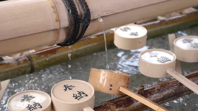 slow motion shot of water and a ladle, used for ritual purification, at fushimi inari shrine in kyoto, japan
