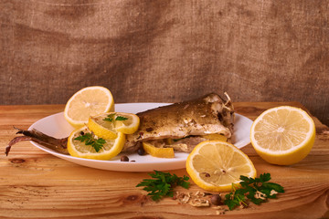 Appetizing baked fish, covered with juicy lemons, garlic and salt on side, above view