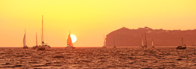 Greece, catamaran boats in the famous sunset of greek island Santorini