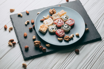 Traditional oriental sweets and nuts: hazelnuts, cashews on a white wooden background. Turkish dessert is the locus of Rahat. View from above. Place under the text.