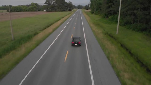 Arial footage of a Chevy Malibu driving down country road.