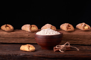 flour in clay bowl products for making cheesecakes on a wooden chopping board. Homemade Cottage cheese cookies on black background. still life composition