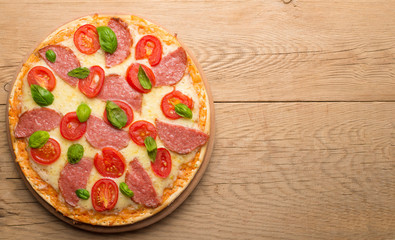 Rustic pizza with salami, mozzarella, cherry and a view of the basilica with a copy of the space.