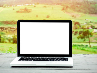 Laptop computer with blank white screen on table,nature background.