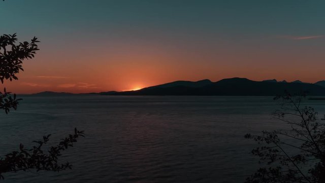 A beautiful sunset falling behind mountains viewed from an outlook in UBC, Vancouver, BC, Canada. Timelapse.