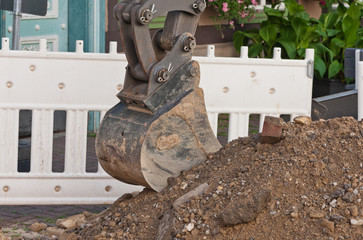 Eine kleine Baggerschaufel - Tieflöffel - ruht auf einem Erdhaufen