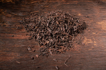 Falling dried black tea leaves isolated on wooden table