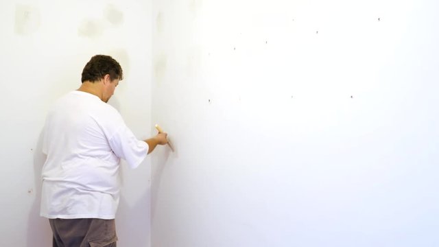 Closeup of a man aligning a wall with spatula and plastering gypsum cardboard wall