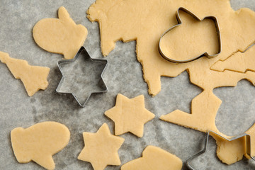 Raw Christmas cookies and cutters on baking parchment, top view