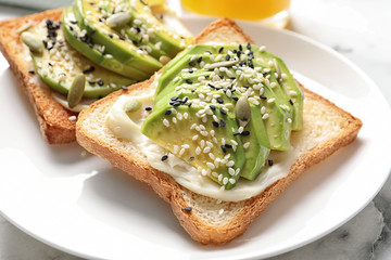 Toast bread with avocado and seeds on plate, closeup