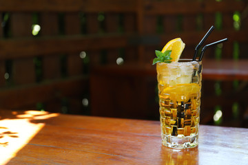 Glass of delicious cocktail with ice on table in bar