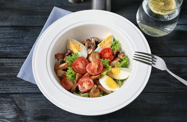 Plate with delicious fresh salad on table