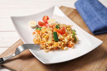 Plate with tasty boiled rice and vegetables on table
