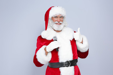 Santa Claus singing into microphone on color background. Christmas music