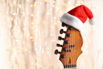 Guitar with Santa hat on blurred background. Christmas music concept