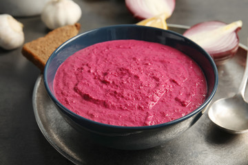 Bowl with tasty beet hummus on dark table
