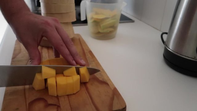 Butternut squash being chopped, sliced and diced on a wooden chopping board