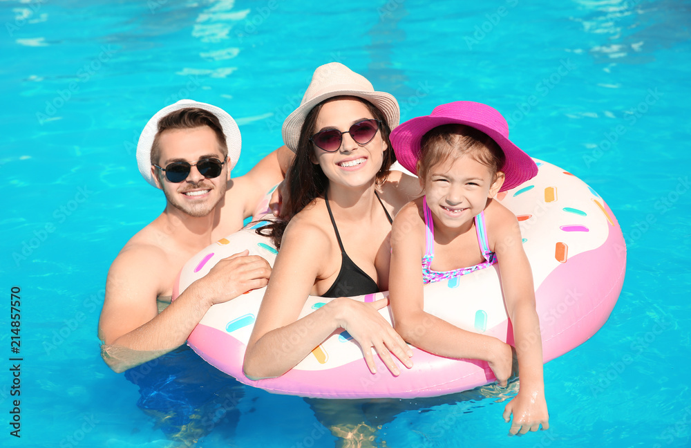 Poster young family with little daughter in swimming pool on sunny day