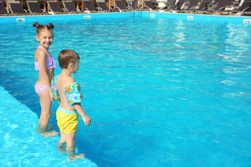 Naklejka premium Little children standing in swimming pool on sunny day