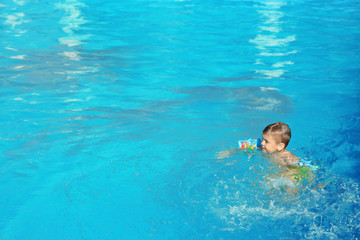 Little boy in swimming pool on sunny day