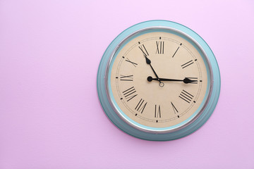 Stylish clock with Roman numerals on color wall. Time of day