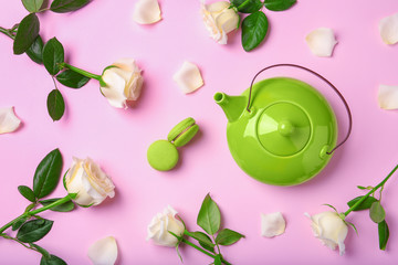Flat lay composition with teapot, macarons and roses on color background