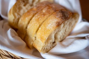 Freshly baked bread in a basket with white cloth liner. Natural light. Selective Focus.